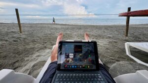 Persona trabajando en la playa con una tablet, disfrutando de vistas al mar