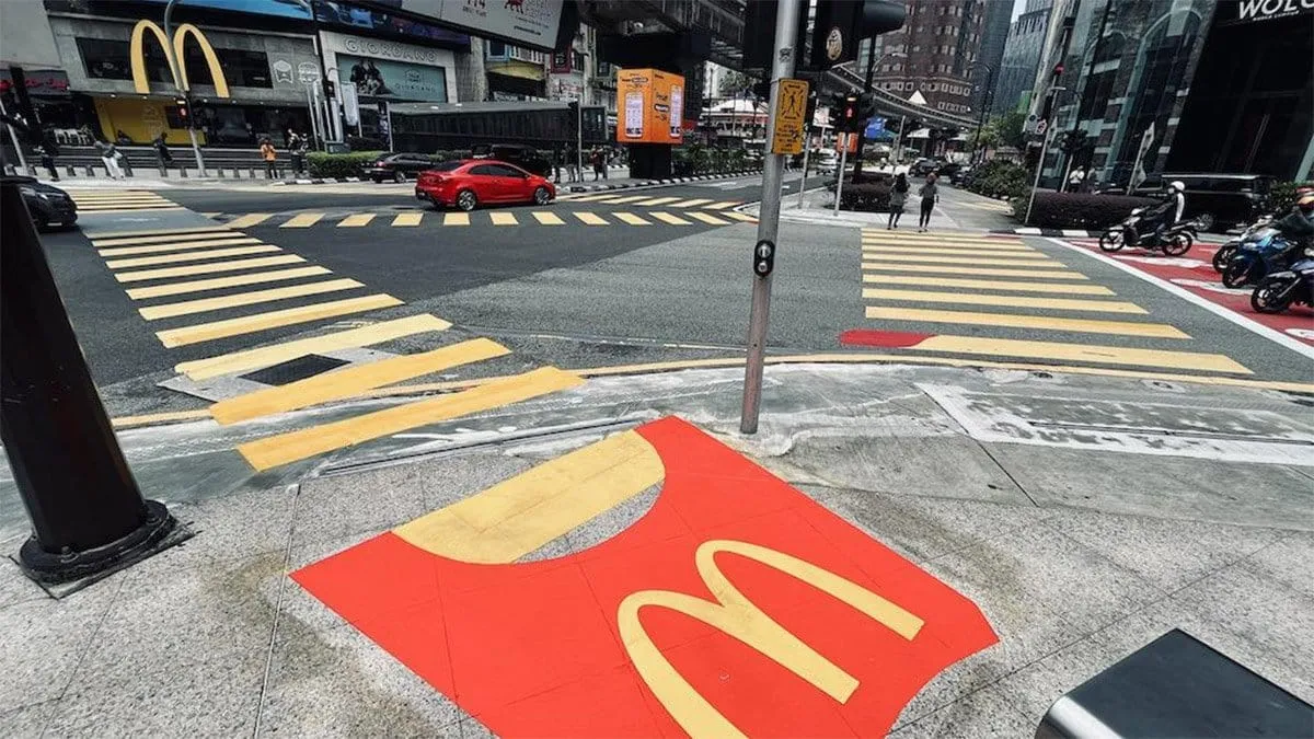 Cruce peatonal con diseño creativo de McDonald’s, donde las líneas amarillas y una base roja simulan una caja de papas fritas, marketing de guerrilla