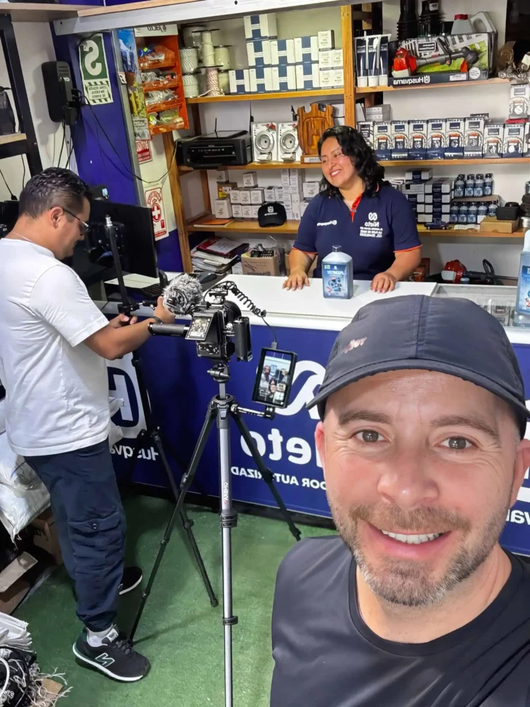 Rodaje de video para el agro en tienda: camarógrafo y vocera en mostrador, con trípode y equipo de grabación.