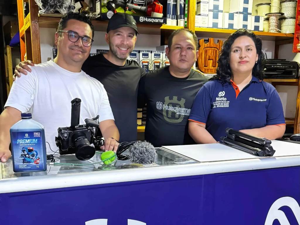 Equipo de producción de video en tienda del agro, con cámaras, trípode y producto Husqvarna sobre el mostrador.